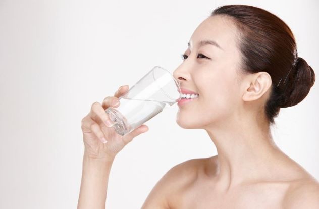 컵에 든 물을 행복한 표정으로 마시고 있는 여성